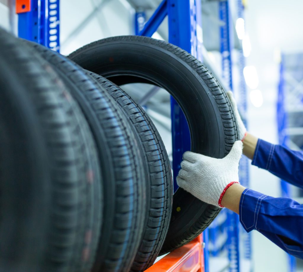 Mechanic picking up a tyre - Tyres & Fitting in Stockport